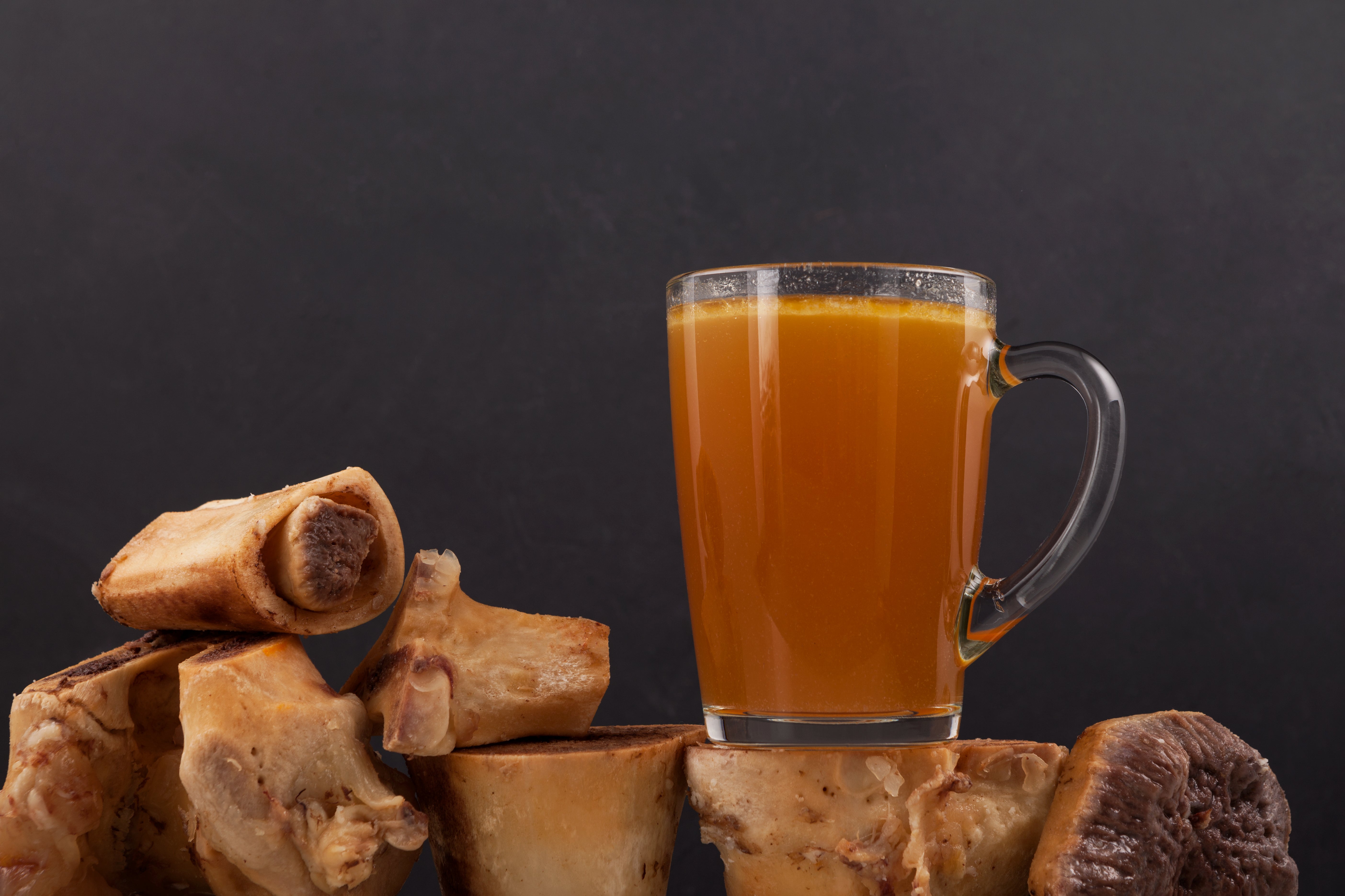 Pasture-raised grass-fed beef bone broth for dogs in a glass mug with marrow bones, a nutritious joint and immune health booster from Rocker Dog.