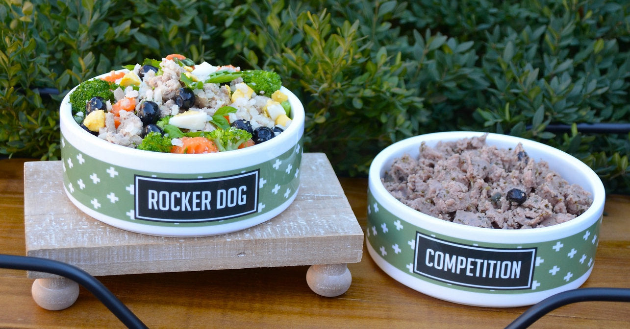 A bowl of Rocker Dog's Fresh Adaptogenic Superfood, with visible whole ingredients, next to a bowl of traditional indiscernible wet dog food
